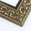 A large, reverse curve profile frame with an intricate leaf design bordered by a geometric outer edge and beaded inner lip.  A dark, matte gold-brown base with gold foil patina for added depth on the topmost points of the design. Strong, solid wood construction.

3.25 " witdth: ideal for large and oversize (extra large) images.